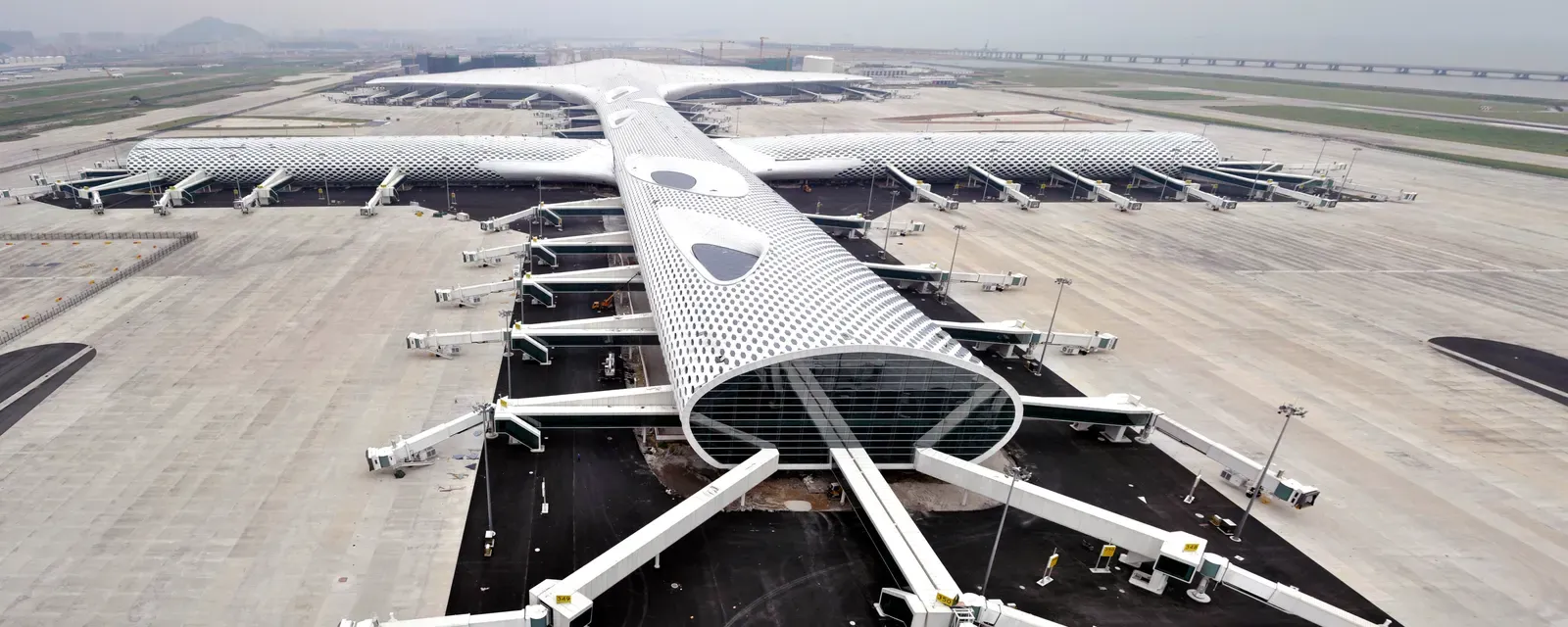 Shenzhen Bao'an International Airport Terminal 3 from above, its white perforated roof spread across the apron