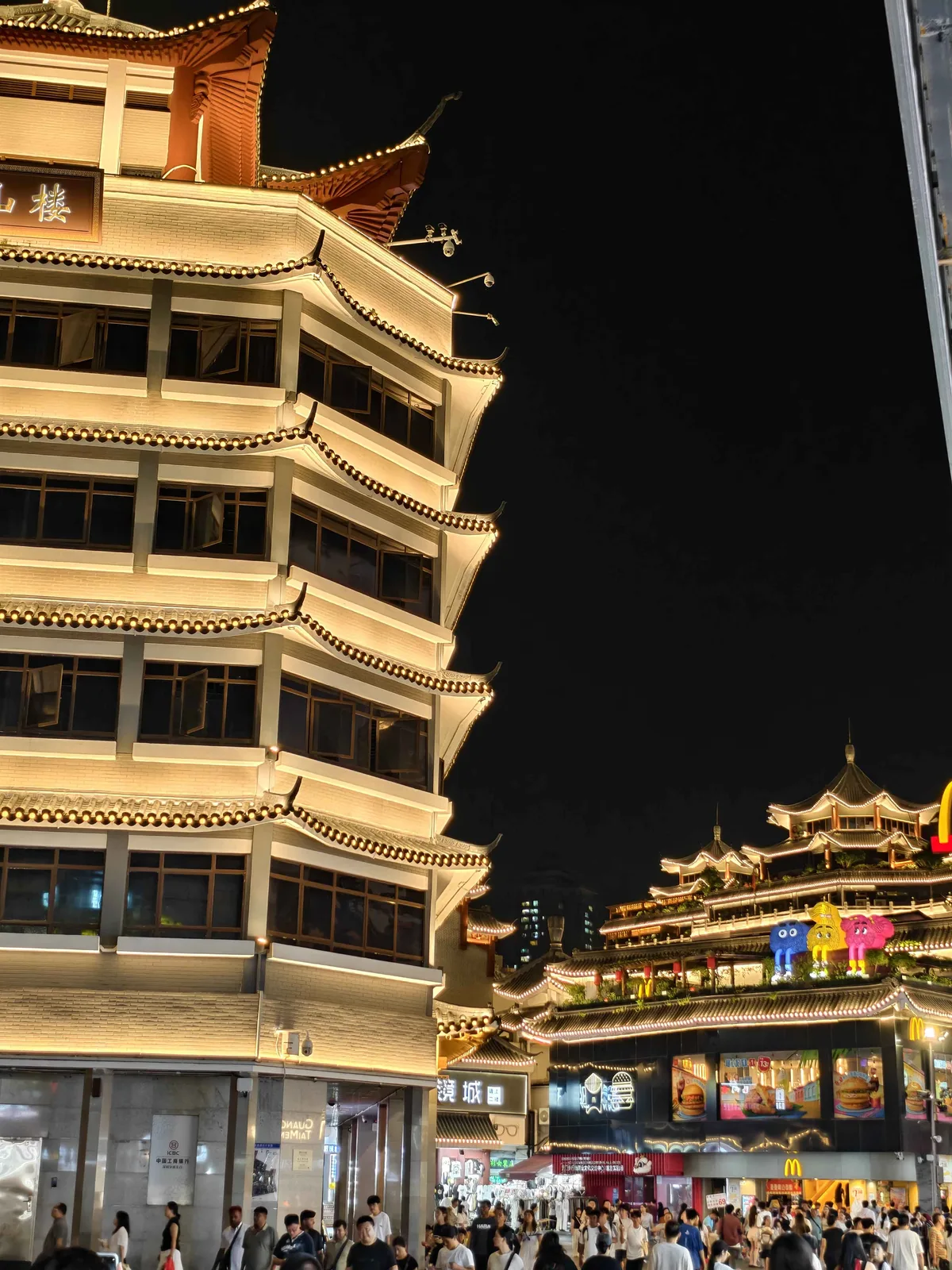 The Dongmen pedestrian street at night, pagoda-roofed buildings lit above the crowd